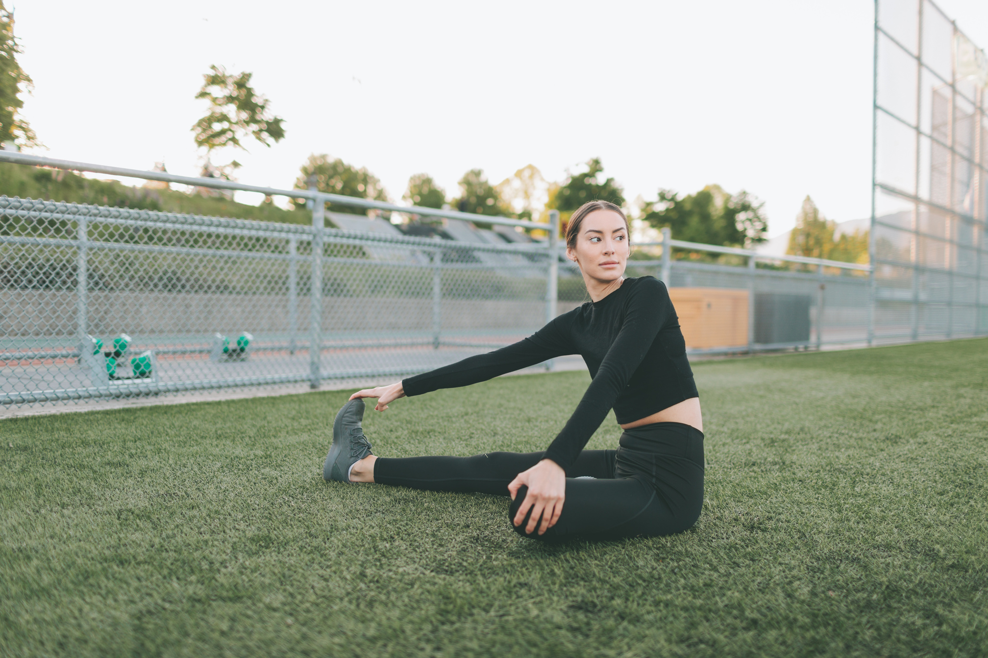 Woman in Black Sportswear Stretching in the Sports Field